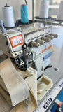 A close-up, high-angle shot of an industrial Siruba overlock sewing machine with multiple thread spools, showing a piece of fabric currently being stitched.